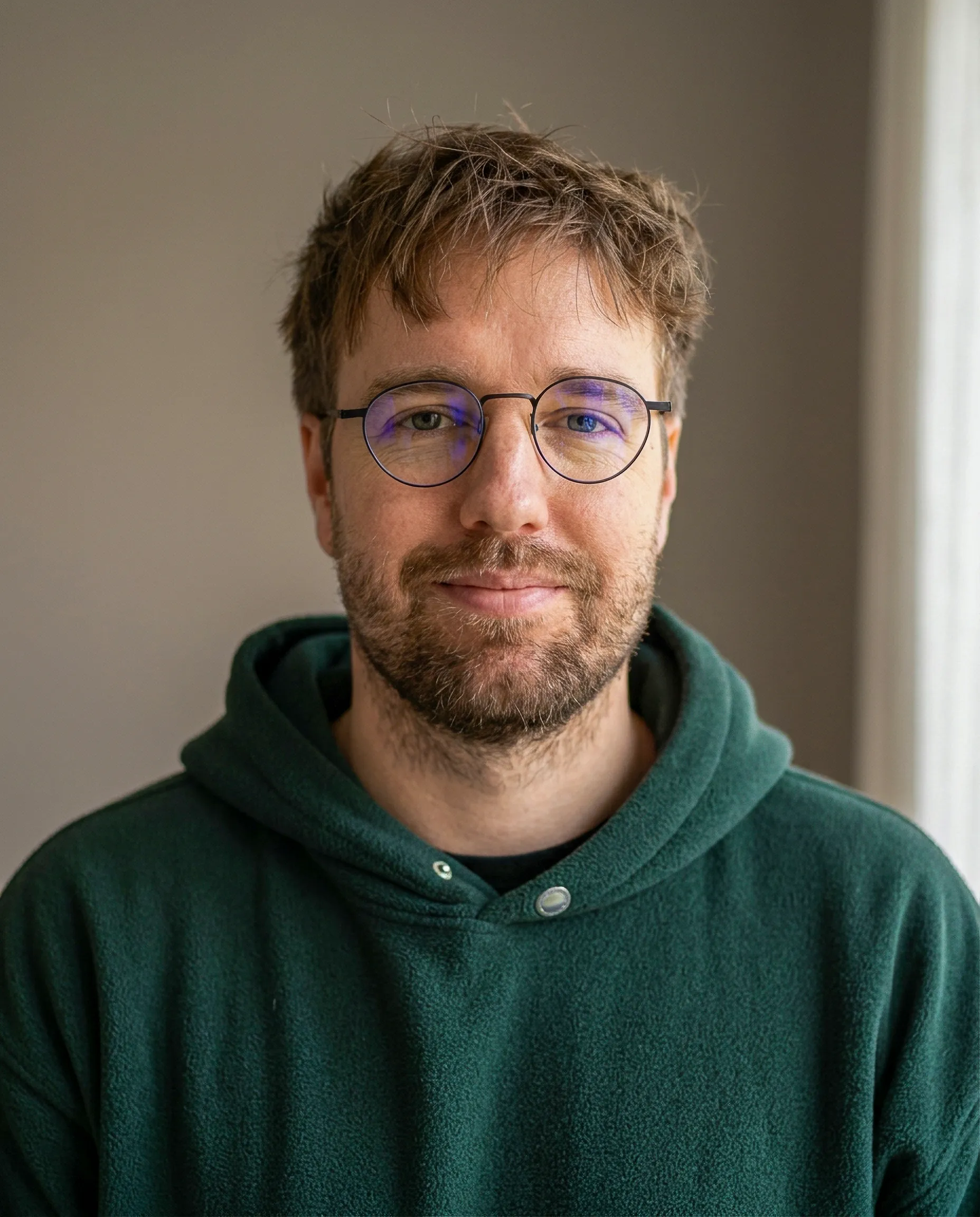 Portrait of Bram Rutten, in glasses and a green hoodie.